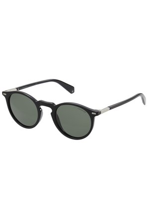 Ochelari de soare rotunzi, cu lentile negre cu nuanță verde închis, cadru din plastic și accente metalice pe tâmple. Textură netedă, design minimalist.