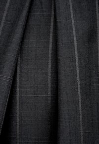 Czarna tkanina o splocie z drobnym, teksturowanym wzorem i subtelnymi pionowymi paskami. Materiał wydaje się być strukturalny i trwały.