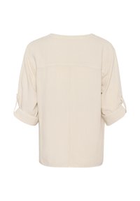 Cremefarvet, løstsiddende bluse med rund halsudskæring, optrukne ærmer og lige kant. Teksturert stof med et minimalistisk design.