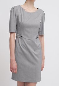 Robe grise à manches courtes en tissu texturé, silhouette ajustée, col rond et deux boutons décoratifs noirs à la taille.