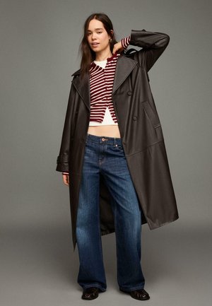 Hosszú fekete bőr ballonkabát, csíkos bordó-fehér rövid pulóver, bő szárú kék farmernadrág, fekete cipő és minimális fémes részletek.