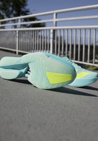 Light blue running shoes with a textured outsole, featuring a bright yellow accent and ADIZERO branding on the side.