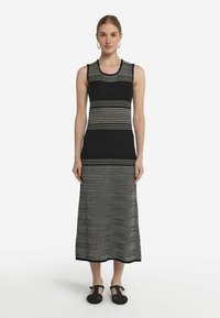 Svart- och vitrandig utan ärmar stickad klänning med en lång, rak silhuett, som har växlande randiga mönster och rund halsringning.