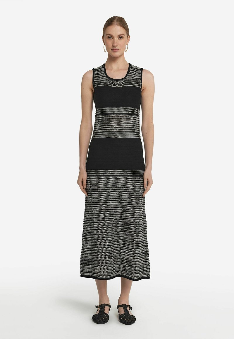 Svart- och vitrandig utan ärmar stickad klänning med en lång, rak silhuett, som har växlande randiga mönster och rund halsringning.