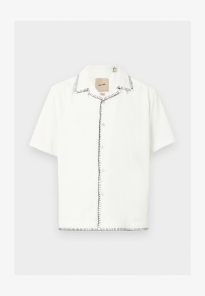 Chemise blanche à manches courtes avec boutons, détails de couture noire sur le col, la ligne de boutons et l'ourlet, présentée sur un fond clair.
