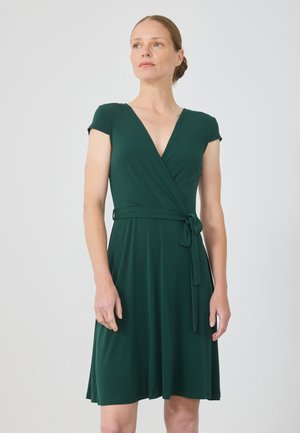 Πράσινο φόρεμα με περιτύλιγμα, με V λαιμόκοψη και κοντά μανίκια, φτιαγμένο από μαλακό, ελαστικό ύφασμα. Διαθέτει ζωνάκι στη μέση, φουσκωτή φούστα και μήκος μέχρι το γόνατο.