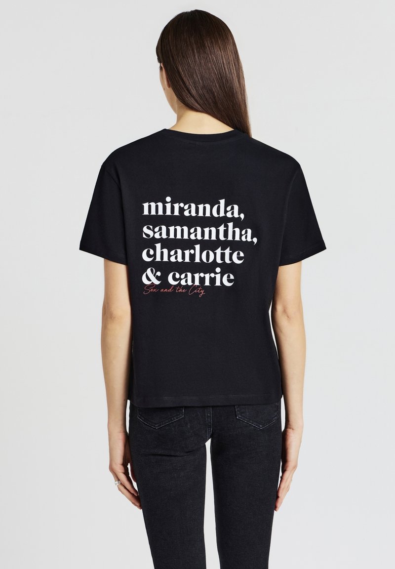 T-shirt in cotone nero con testo bianco sul retro: "miranda, samantha, charlotte & carrie" e "Sex and the City" in rosso. Vestibilità casual.