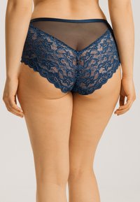 Koronkowe majtki hipster w ciemnoniebieskim kolorze z przezroczystymi siateczkowymi detalami. Kwiatowe wzory i falbany podkreślają projekt, z satynowym paskiem w talii.