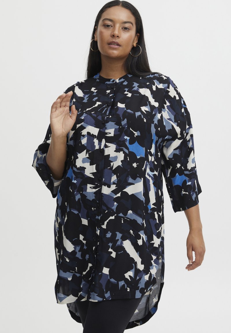 Blusa fluida e a fantasia nera, blu e bianca; presenta una chiusura con bottoni, maniche a 3/4 e un orlo arrotondato. Tessuto morbido.