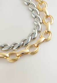 Metallkettengeschenk mit ineinander verknüpften silber- und goldfarbenen Gliedern; glänzende, glatte Textur mit verschiedenen Designs für jede Farbe.