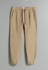 Beige, schmal zulaufende Jogginghosen mit elastischem Bund, Kordelzug, Seitentaschen und geschwungenen Nähten, hergestellt aus einem glatten, leichten Stoff.