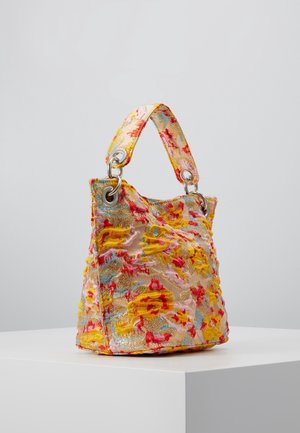 Kleine Handtasche mit kurzem Griff, aus strukturiertem Stoff in gelben, roten, rosa und blauen Blumenmustern, mit Metallösen, auf weißem Podest präsentiert.