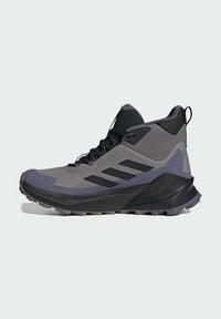 Chaussures de sport grises et noires avec une tige en mesh texturé, une semelle en caoutchouc, un bout renforcé et trois bandes noires sur le côté.