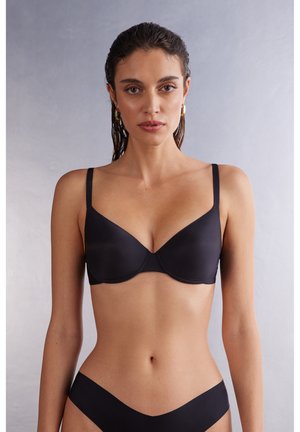 Zwarte beha met een gladde, matte textuur, gevormde cups, verstelbare bandjes en een subtiele naaddetails, gecombineerd met bijpassende zwarte slip.