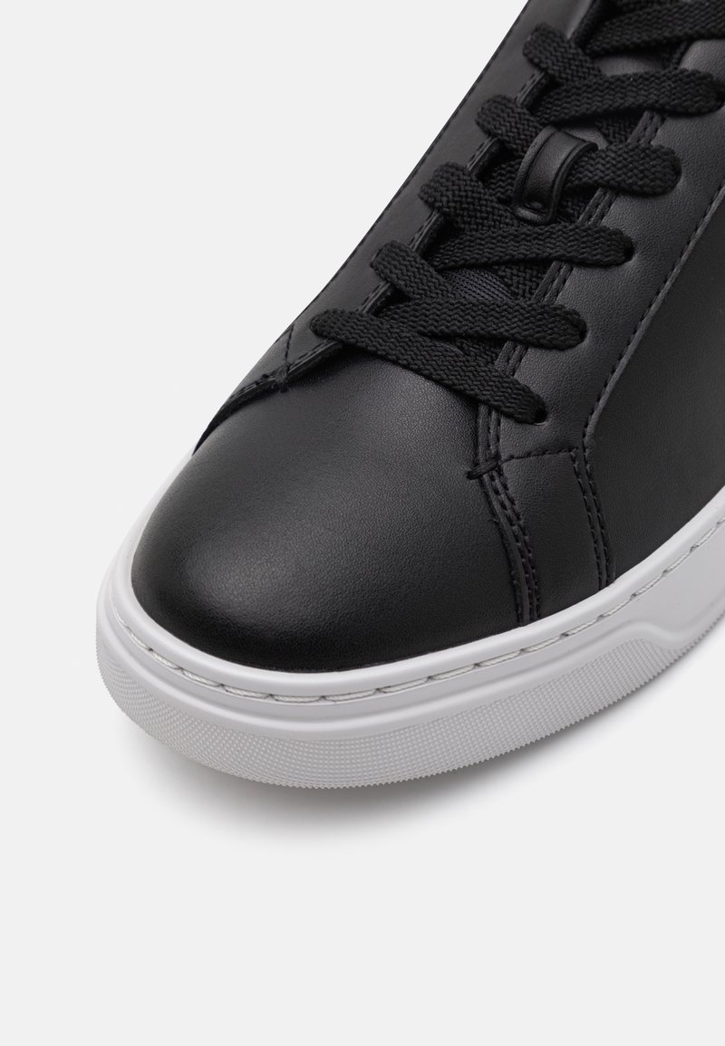 Schwarze Leder-Sneaker mit runder Zehenpartie, strukturiertem Obermaterial, weißer Gummisohle und schwarzen Schnürsenkeln. Sichtbare Steppnähte an den Seiten.