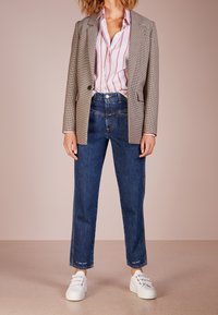 Rutig grå blazer, vit skjorta med röda ränder, högmidjade denimjeans och vita sneakers. Avslappnad outfit med blandade texturer.