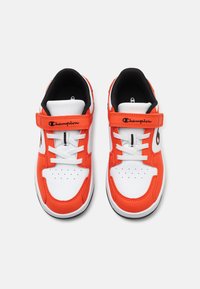 Red and white athletic shoes with a synthetic upper, lace closure, hook-and-loop strap, and perforated toe for ventilation.