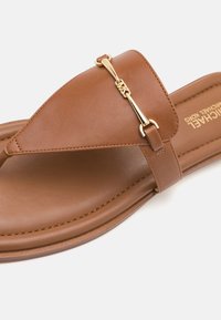 Brune lær slidesandal med en thong-design, som har detaljer med guldfarve og en flad sål, fremhævet af minimalistisk syning.