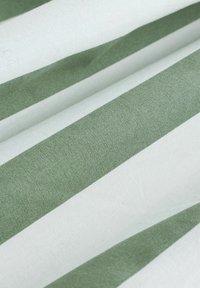 Nahaufnahme eines Stoffs mit breiten horizontalen Streifen in Hellgrün und Weiß, der Textur und leichte Falten zeigt.