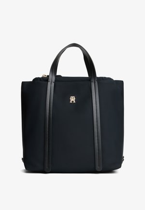 Zwarte tote-tas met twee lange leren handvatten en een klein gouden logo middenvoor tegen een witte achtergrond.