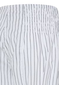 Tissu blanc avec de fines rayures verticales noires et une taille élastique froncée, montrant de légers plis et une texture.