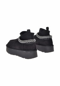 Stivaletti neri in suede con collare in maglia e decorativo punto zigzag bianco, dotati di una spessa suola in gomma nera.