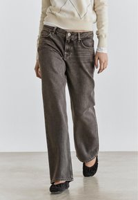 Gray wide-leg jeans in a soft, textured denim fabric, featuring front pockets and a high waist, paired with a light knit sweater.