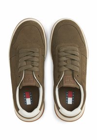 Brązowe zamszowe sneakersy z sznurowanym wzorem, białe skórzane akcenty, beżowa gumowa podeszwa i wytłoczone logo na języku, widok z góry.