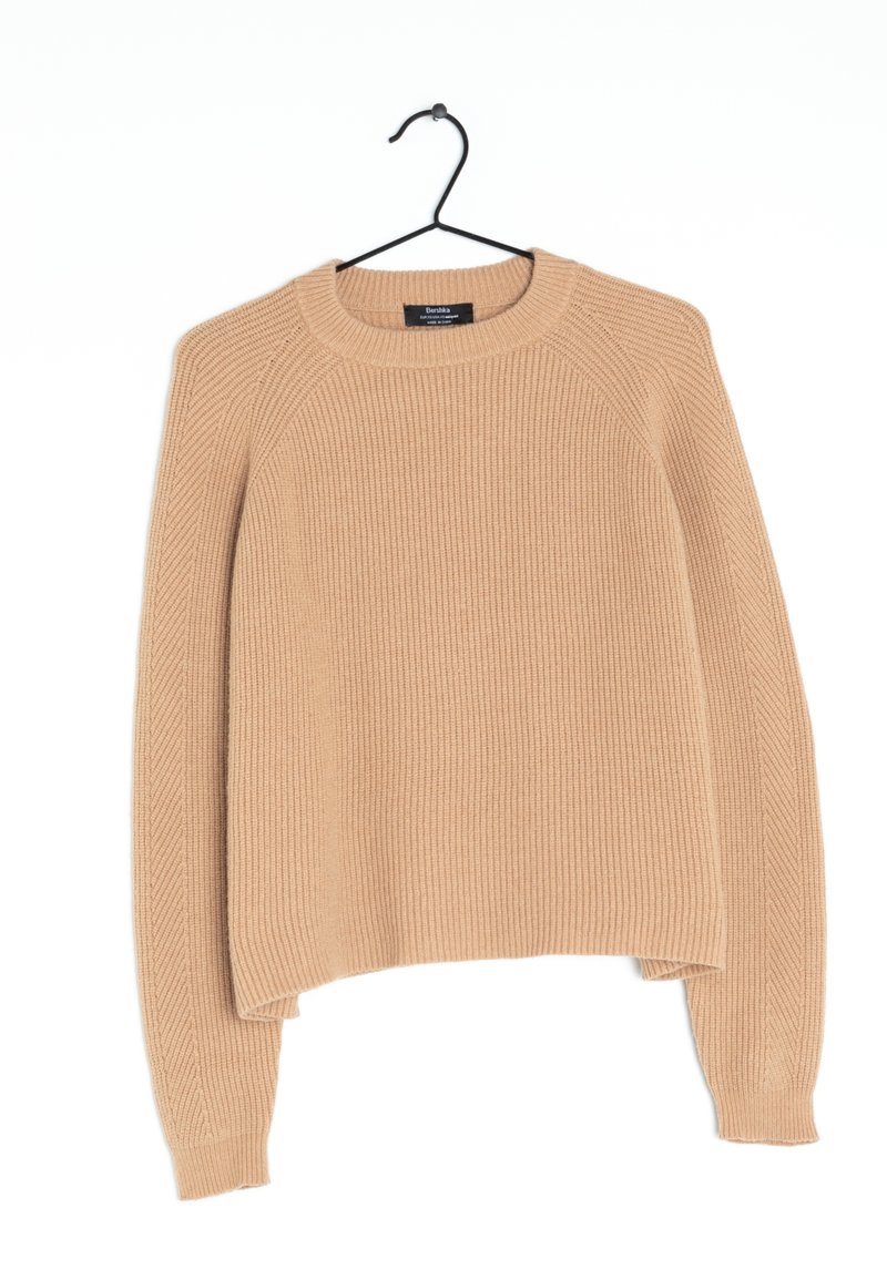 Beige geribde trui met een ronde halslijn en raglanmouwen, voorzien van een gestructureerde stof en een cropped zoom. Hangt aan een zwarte haak.