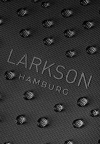 Čierna textúrovaná tkanina s embosovanými bodkami a názvom značky "LARKSON HAMBURG" v elegantnom písmovom štýle, vytvárajúca moderný vzhľad.