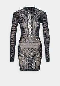 Juoda ilgomis rankovėmis suknelė, kuri turi tinklelio ir deimanto raštus, su raišteliu priekyje ir metaliniais akcentais, pabrėžianti prigludusią siluetą.