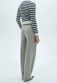 Striped cropped sweater in navy and cream, paired with high-waisted, wide-leg trousers in light gray, featuring a back pocket detail.