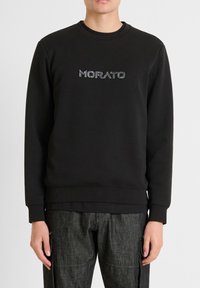Sudadera negra con cuello redondo y puños acanalados. Presenta la palabra "MORATO" en un detalle estampado en el pecho. Textura suave.