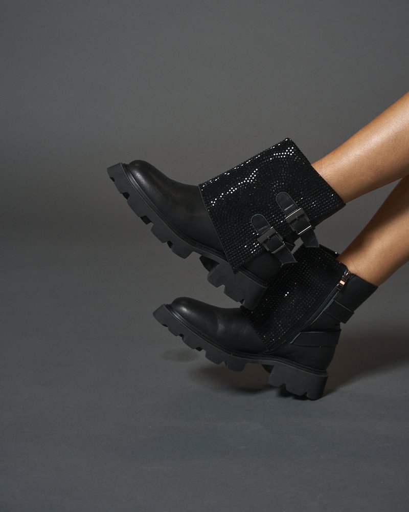 Botas de tobillo negras con punta de cuero mate, parte superior de lentejuelas negras texturizadas, correas ajustables y suela de goma gruesa.