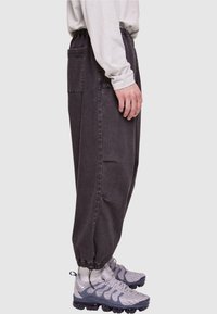 Cargo bukser i mørkegrå denim med elastisk talje, tapered manchetter og sidelommer. Bæret med grå sportssko.