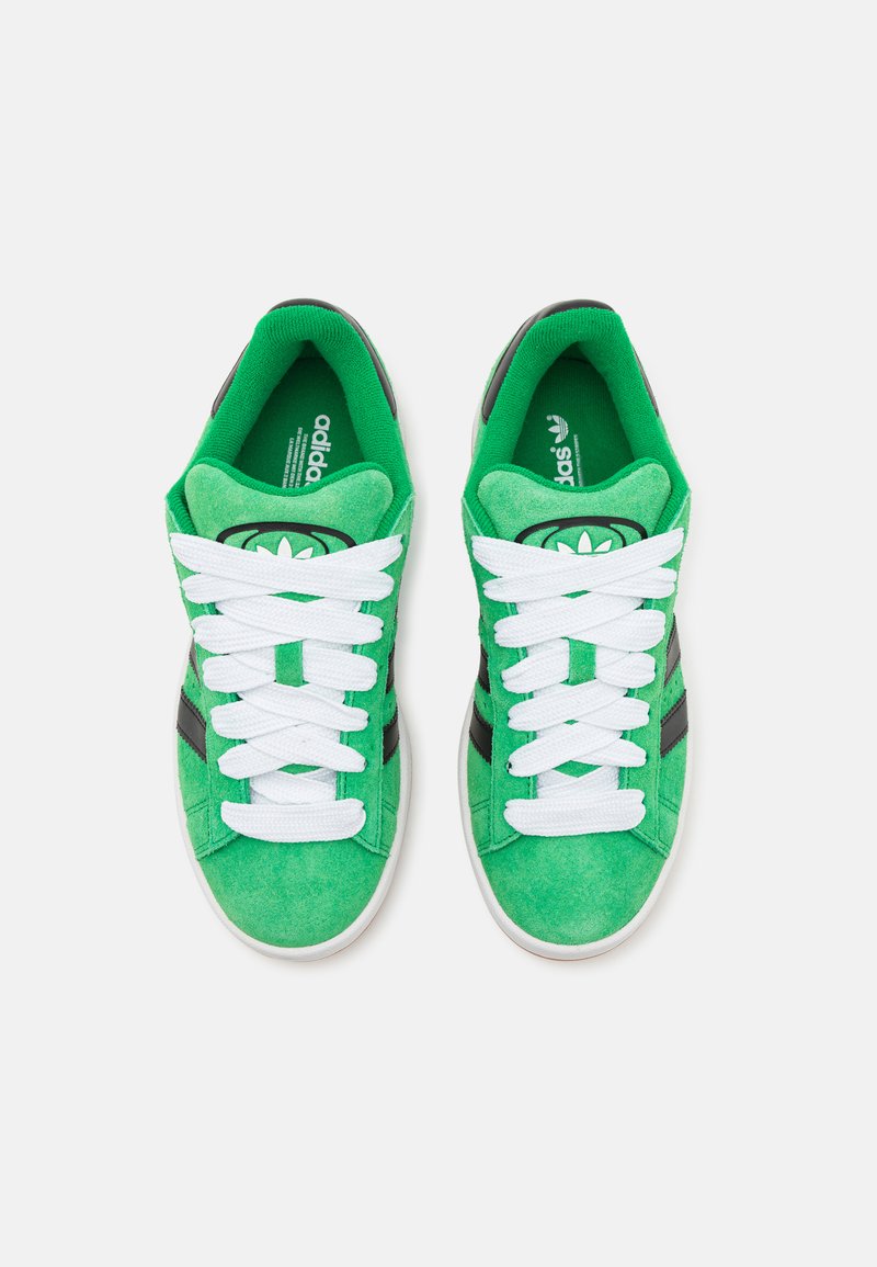 Zielone zamszowe sneakersy z białymi sznurówkami i czarnymi paskami. Okrągły przód i wyściełany kołnierz. Marka "adidas" na wkładce.