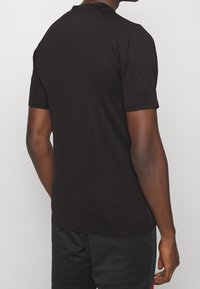 Camiseta negra de manga corta con cuello redondo, textura suave, diseño ajustado y detalle de costura sutil en los hombros.