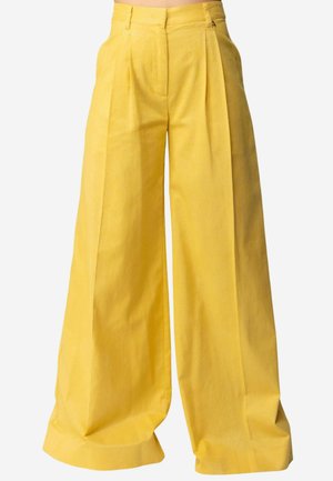 Pantaloni gialli a vita alta, a gamba larga, con pieghe frontali, passanti per cintura visibili e una vestibilità ampia e fluida.