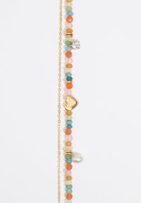 Pulsera de cuentas multicolor que presenta piedras naranjas, rosas y verdes, acentos dorados y un colgante en forma de corazón con un detalle de perla.