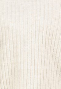 Cremefarbener gerippter Strickstoff mit vertikalen strukturierten Linien, der weiche und gemütliche Materialdetails zeigt.