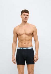 Fekete pamut boxer rövidnadrág világoskék elasztikus derékrésszel, amelyen Nike logó található. Szorosan illeszkedik, a comb közepéig ér.