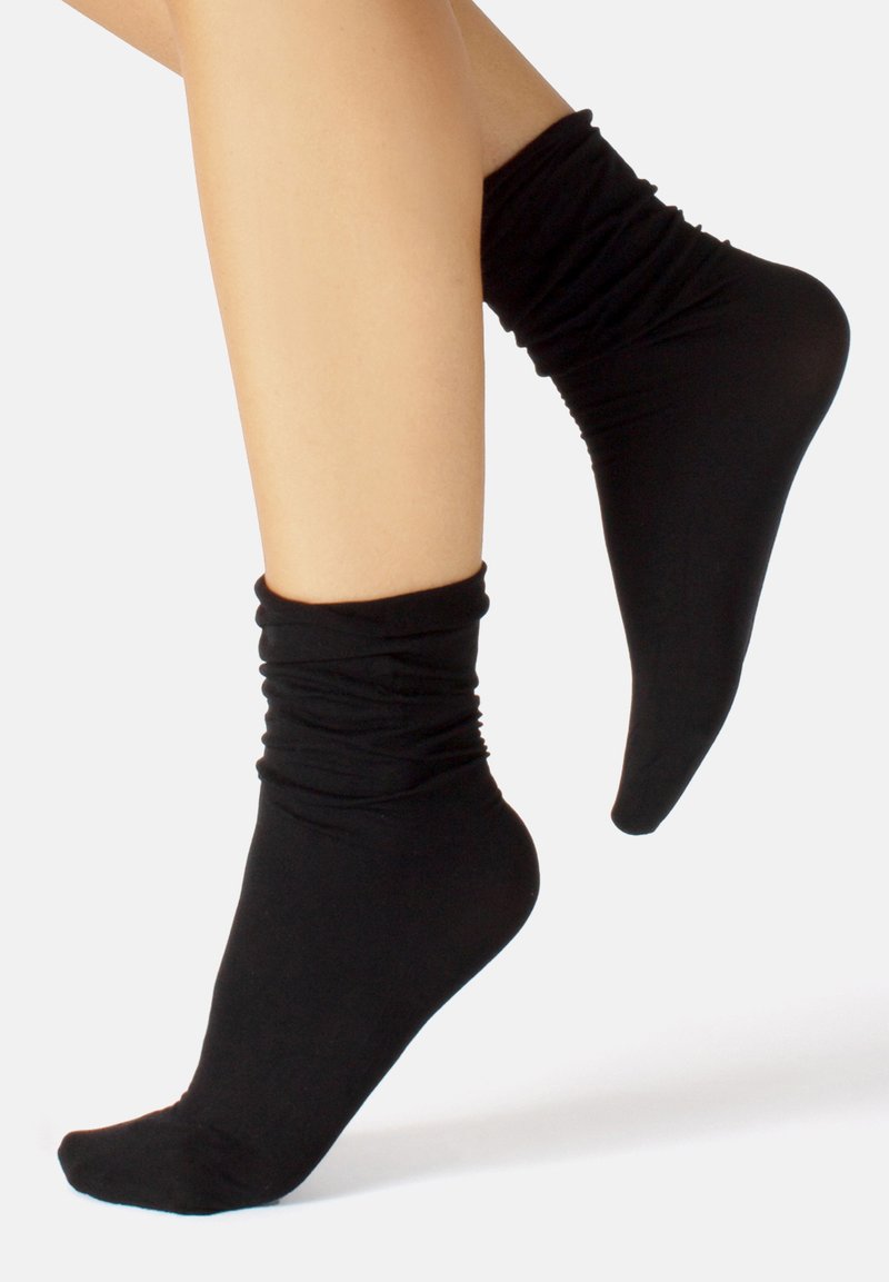 Schwarze Knöchelsocken aus dehnbarem Material, mit einem gerafften oberen Saum und glatter Textur. Geeignet für legere Outfits.