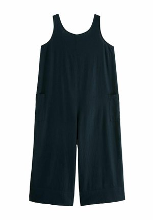 Combinaison noire sans manches en tissu léger. Dotée de jambes larges, de deux poches latérales et d'une texture lisse.