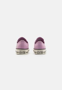 Sneaker in tela viola con design a basso profilo, suole in gomma e branding a contrasto in bianco e nero sul tallone.