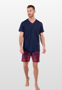 Marinblå bomulls T-shirt med V-hals och bröstficka, kombinerad med r�öda shorts med blommönster och blå accenter, avslappnad passform, lätt tyg.