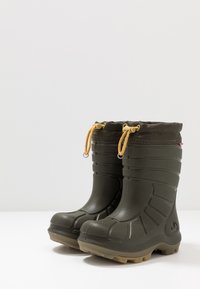 Botas de goma verdes con un acabado texturizado, punta redondeada y suela reforzada. Presentan un cordón ajustable marrón en la parte superior.