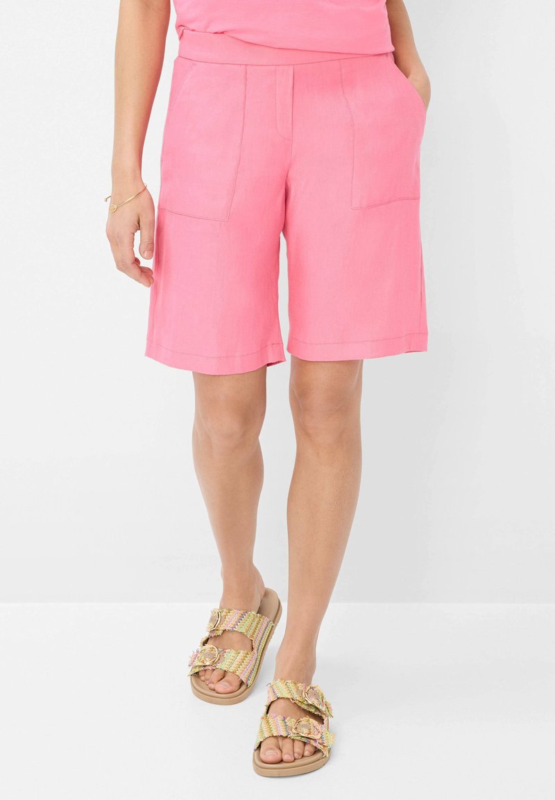 Roze linnen shorts met twee achterzakken en een relaxte pasvorm, gecombineerd met slide-sandalen in meerdere kleuren met decoratieve gespen.