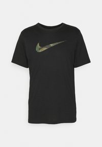 Camiseta de algodón negra con cuello redondo. Presenta un logo de la marca Nike en el centro, con un diseño de camuflaje. Mangas cortas, corte estándar.