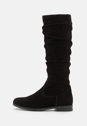 Bottines noires en suède, montantes, au design décontracté, avec un bout arrondi et un petit talon noir. Texture lisse avec des coutures visibles.