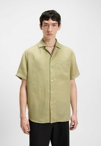 Korte mouwen, lichtgroen linnen shirt met een borstzak aan de linkerkant, knoopsluiting en een ontspannen pasvorm. Soepele structuur en subtiele glans.